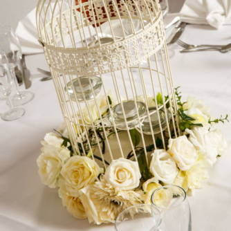 Close up of white bird cage with white flowers as table decoration